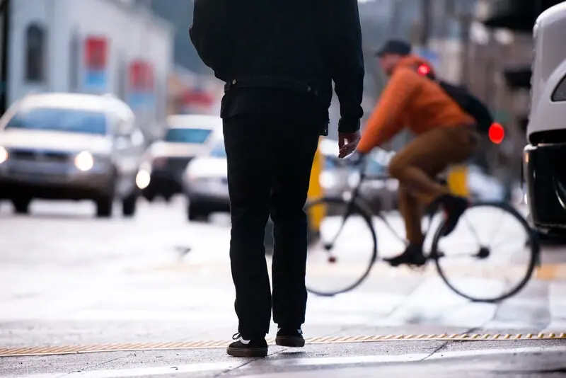 A cyclist and a pedestrian crossing paths in city traffic
