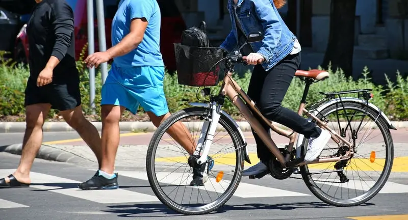 A cyclist riding close to pedestrians at a crosswalk A cyclist riding close to pedestrians at a crosswalk