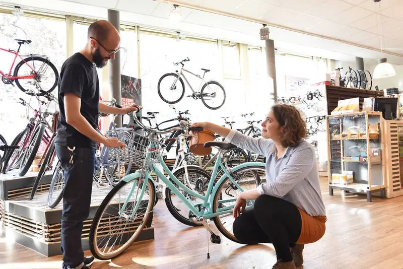 Shoppers looking over a bike with a salesperson in a bike shop Shoppers looking over a bike with a salesperson in a bike shop