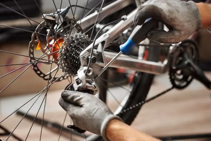 Mechanic adjusting a worn rear derailleur and cassette on a used bike Mechanic adjusting a worn rear derailleur and cassette on a used bike