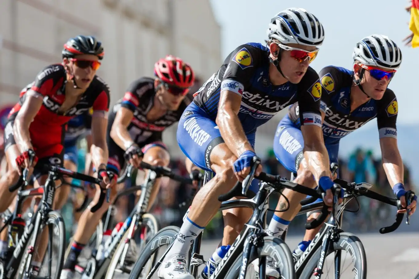 Road cyclists racing in a peloton wearing sponsored team kit