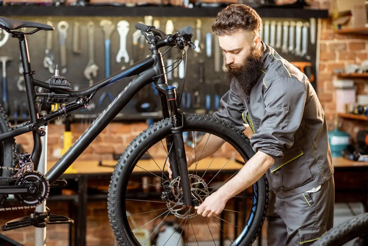 A bike shop mechanic inspecting a mountain bike in a repair stand A bike shop mechanic inspecting a mountain bike in a repair stand