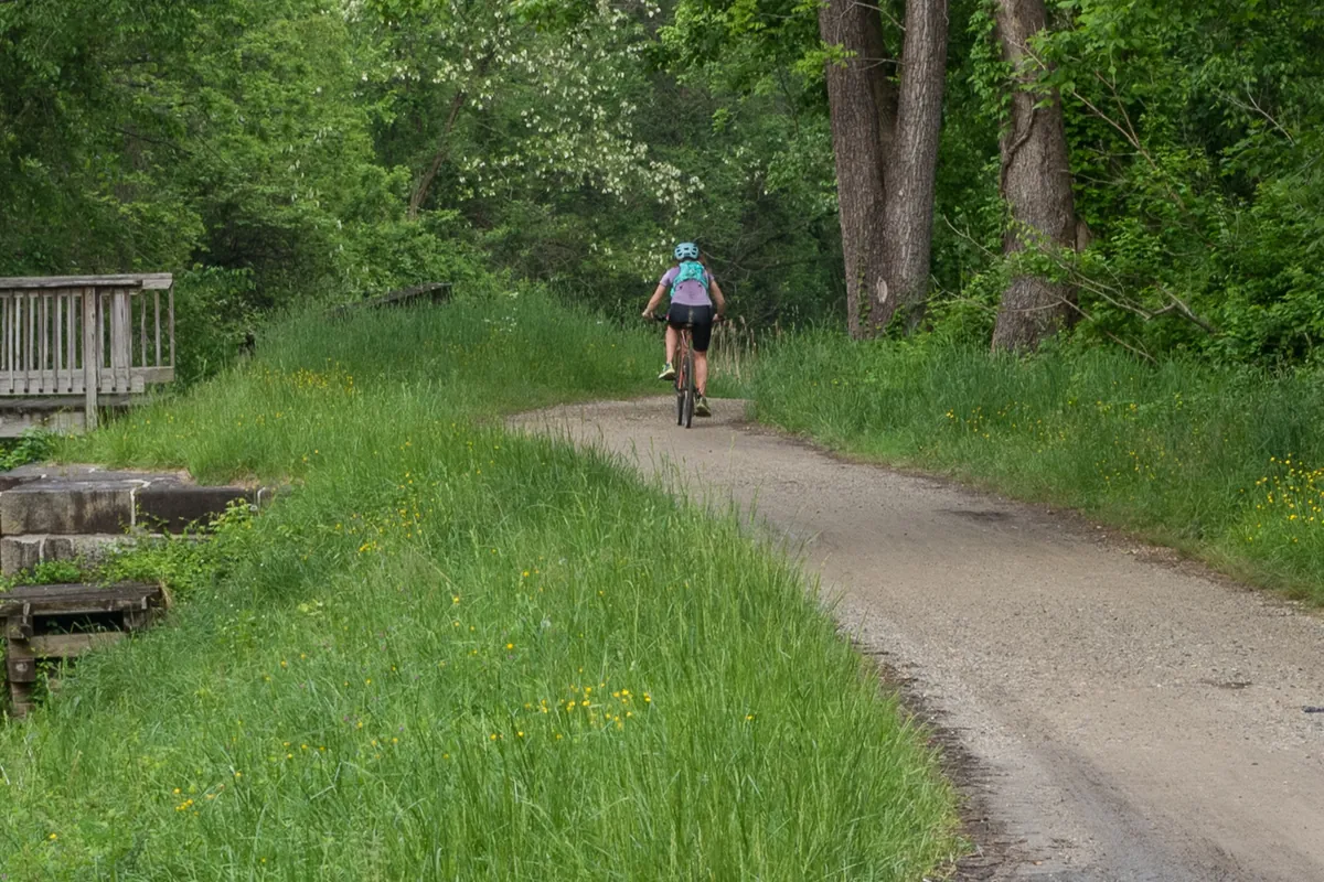 Cyclist riding a wooded trail past an old canal lock in Maryland
