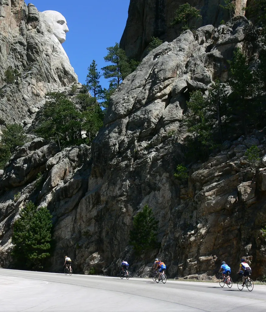 Cyclists riding beneath Mount Rushmore on the Peter Norbeck Scenic Byway